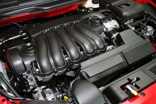 Red car engine bay with detailed components, cleaned during engine detail