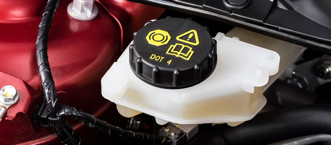 Close-up of a red car’s engine with a brake fluid reservoir cap