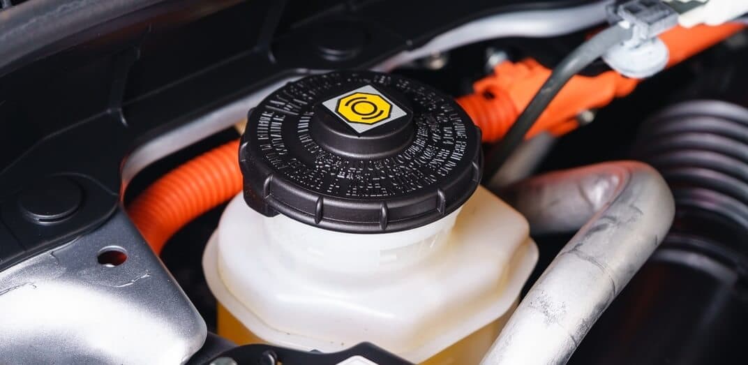Close-up of a red car’s engine with a brake fluid reservoir cap
