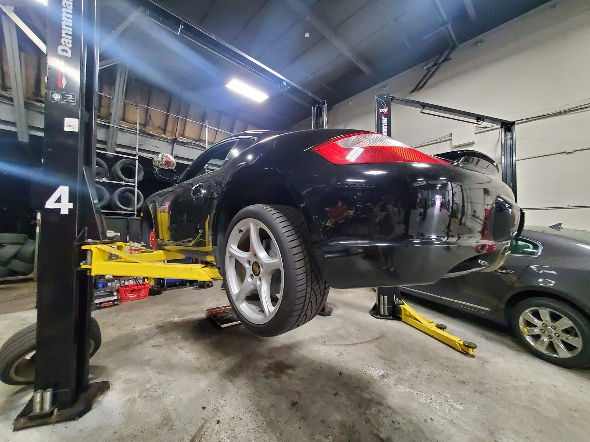 Dark sedan lifted in a garage, undergoing brake pads replacement